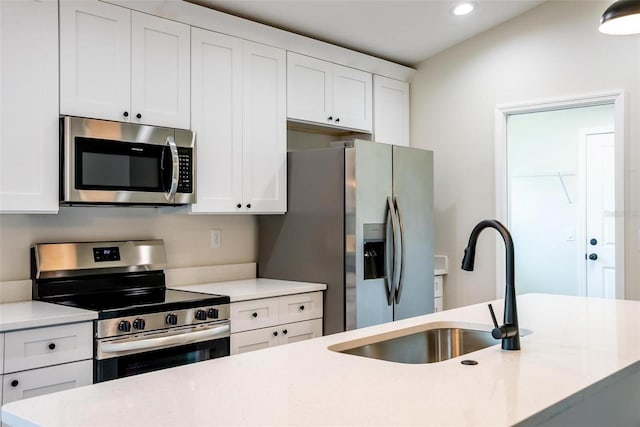 kitchen with stainless steel appliances, white cabinetry, and sink