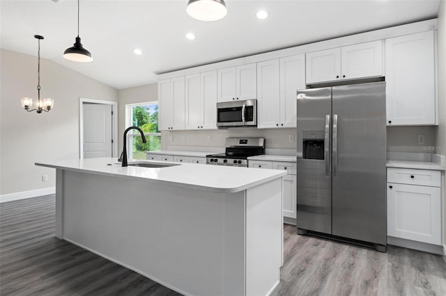 kitchen with stainless steel appliances, white cabinets, sink, and an island with sink