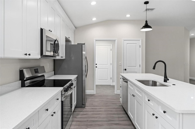 kitchen with decorative light fixtures, stainless steel appliances, a kitchen island with sink, and white cabinets