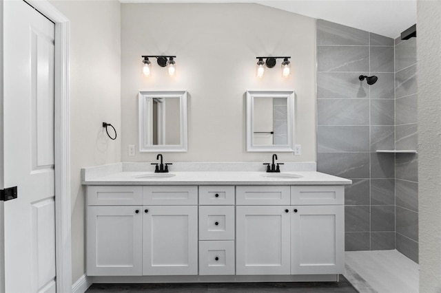 bathroom featuring lofted ceiling, a tile shower, and vanity