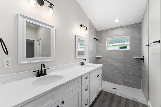 bathroom featuring wood-type flooring, vanity, and tiled shower