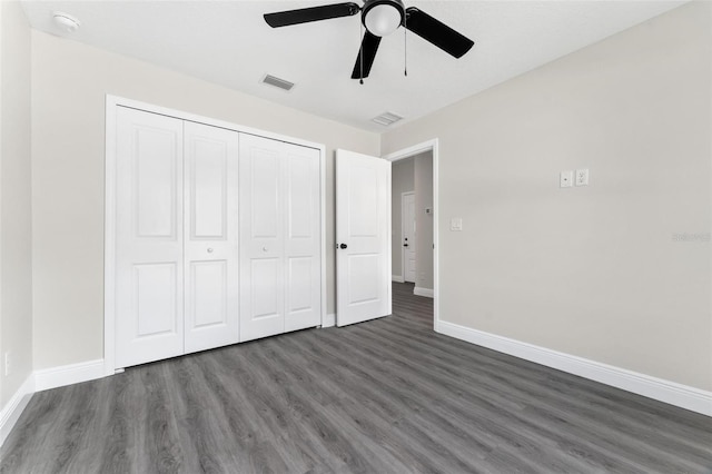 unfurnished bedroom featuring dark wood-type flooring, ceiling fan, and a closet