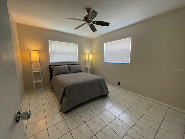 bedroom featuring light tile patterned floors, baseboards, multiple windows, and ceiling fan