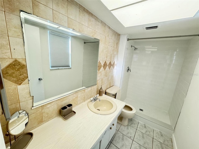 bathroom featuring tile floors, a tile shower, vanity with extensive cabinet space, and tile walls