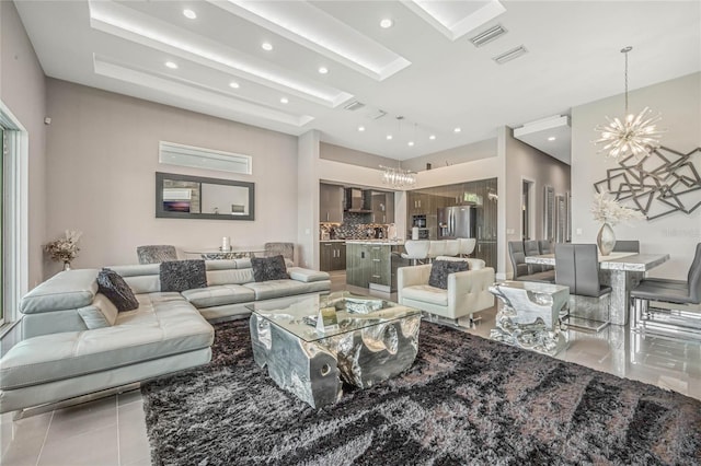 tiled living room featuring a tray ceiling and a chandelier