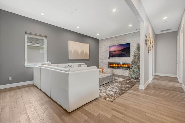 living room featuring a stone fireplace and light wood-type flooring