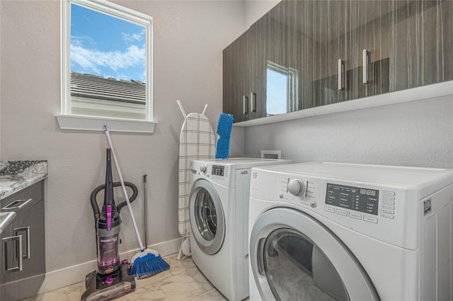 clothes washing area featuring a healthy amount of sunlight, cabinets, and washer and dryer