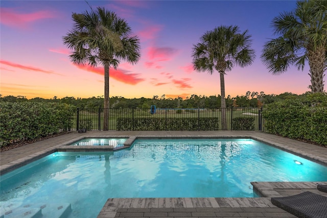 pool at dusk featuring an in ground hot tub