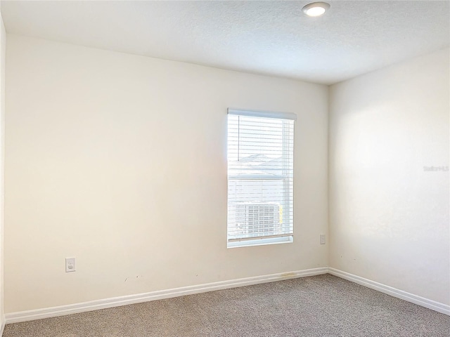 carpeted spare room featuring baseboards and a textured ceiling