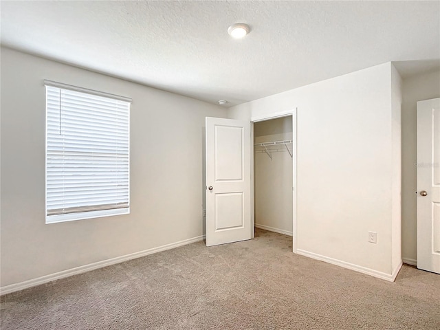 unfurnished bedroom featuring light colored carpet, a closet, and a textured ceiling