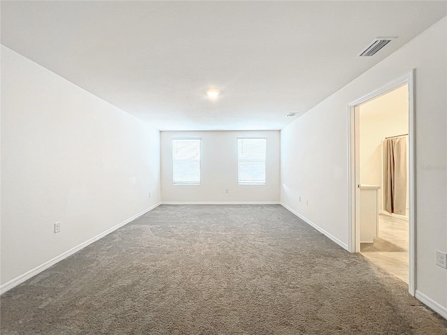 carpeted empty room featuring visible vents and baseboards