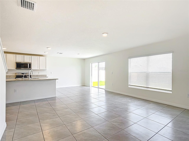 unfurnished living room featuring light tile patterned floors, baseboards, and visible vents