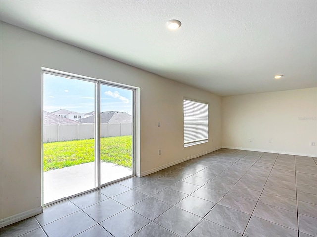 unfurnished room featuring light tile patterned flooring, baseboards, and a textured ceiling