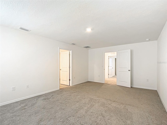 carpeted empty room featuring a textured ceiling