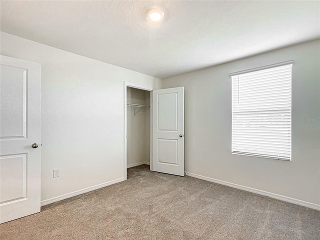 unfurnished bedroom with a closet, light colored carpet, and baseboards