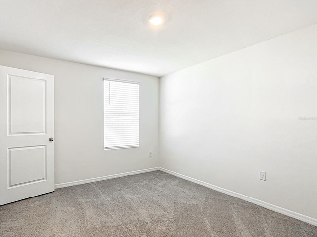 carpeted spare room featuring baseboards