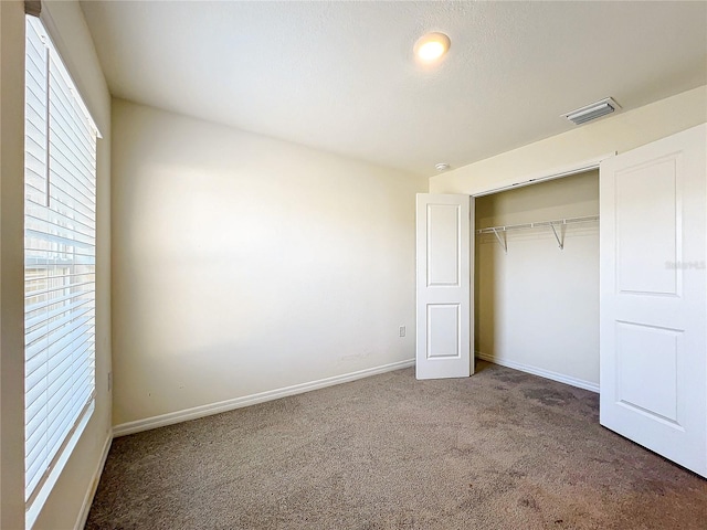 unfurnished bedroom with a closet, visible vents, baseboards, and carpet