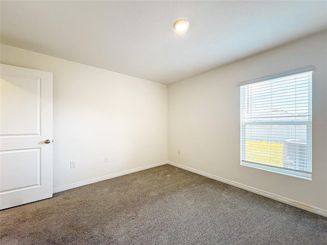 carpeted spare room featuring baseboards