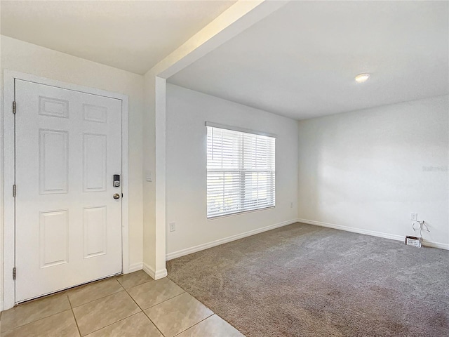 entryway featuring light tile patterned floors, light colored carpet, and baseboards