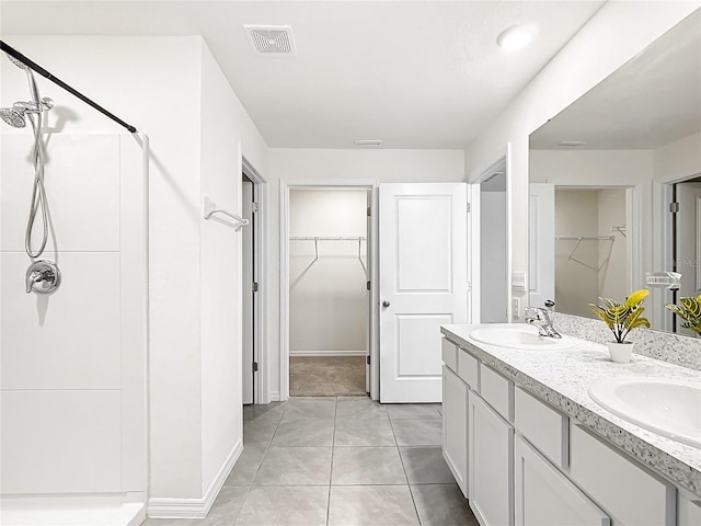 full bath featuring tile patterned flooring, visible vents, walk in shower, and a sink