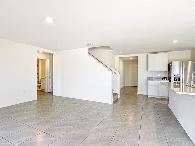 unfurnished living room with light tile patterned floors, visible vents, and stairs