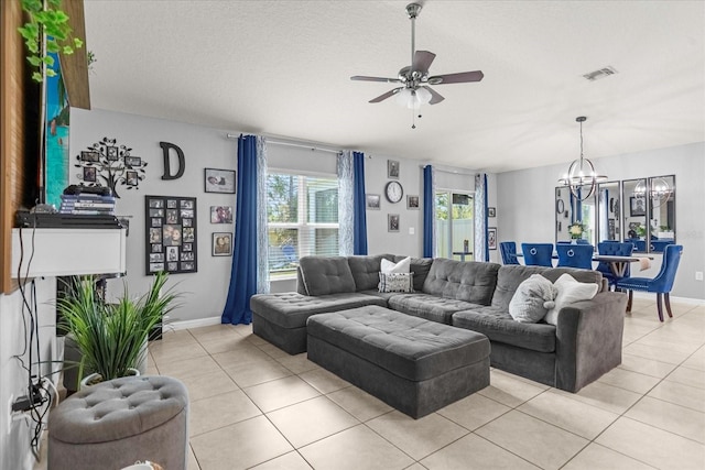 living room with ceiling fan with notable chandelier, light tile patterned flooring, and a textured ceiling