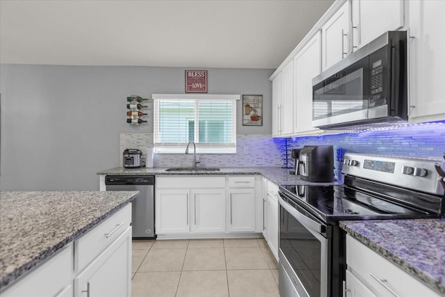 kitchen featuring white cabinetry, sink, light stone countertops, light tile patterned floors, and appliances with stainless steel finishes