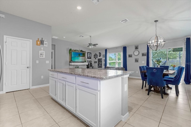 kitchen featuring ceiling fan with notable chandelier, pendant lighting, light tile patterned floors, a center island, and white cabinetry