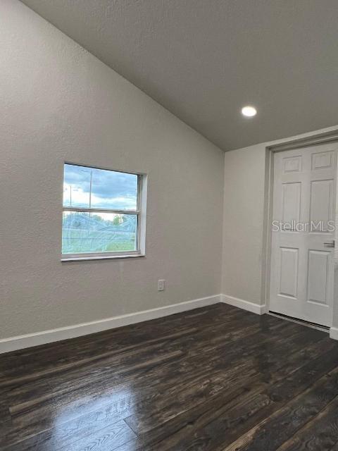 1526 Lakewood Rd, Davenport, FL 33837 - unfurnished bedroom with dark wood-style floors, vaulted ceiling, and recessed lighting