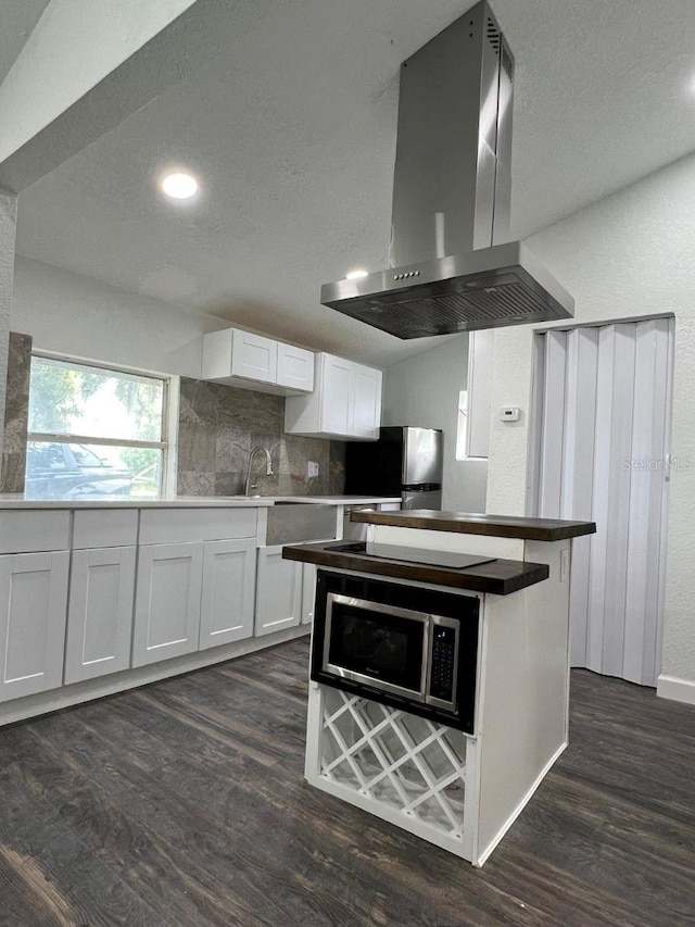 kitchen with island exhaust hood, white cabinetry, dark hardwood / wood-style floors, and appliances with stainless steel finishes