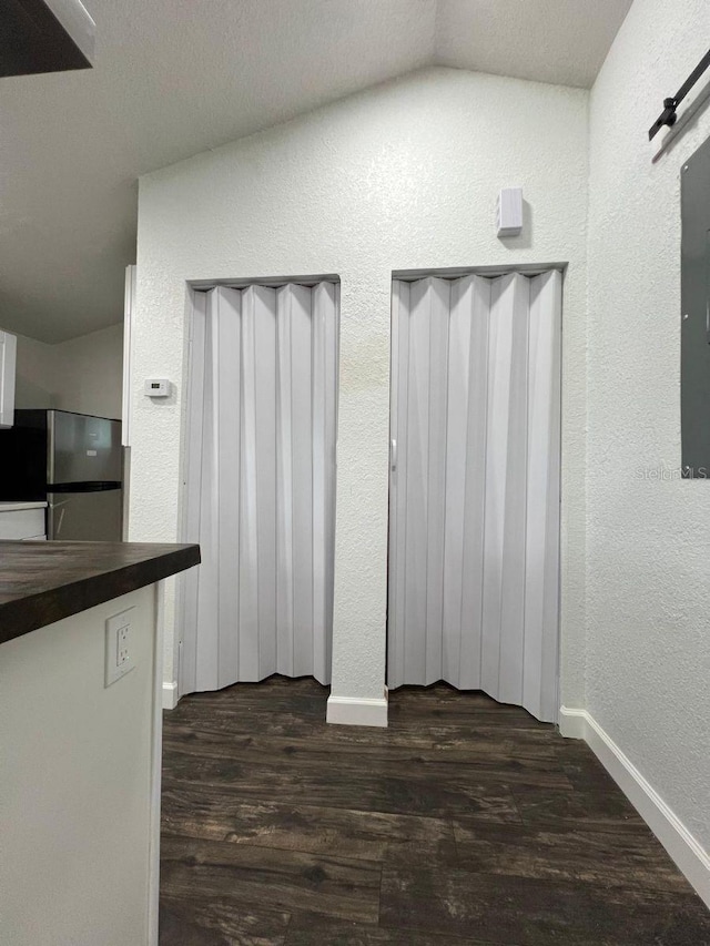 interior space with a barn door, dark hardwood / wood-style flooring, and lofted ceiling