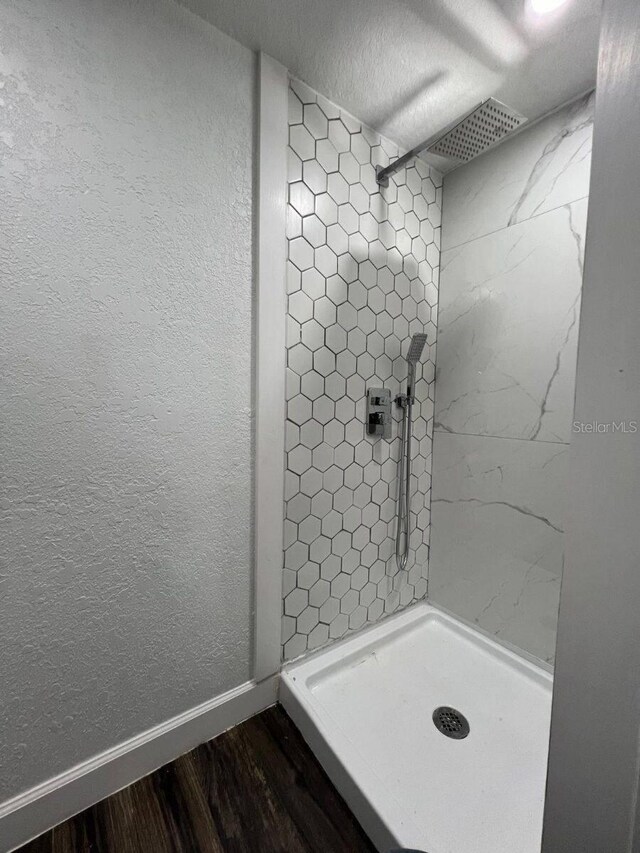 bathroom with a tile shower, a textured ceiling, and hardwood / wood-style flooring