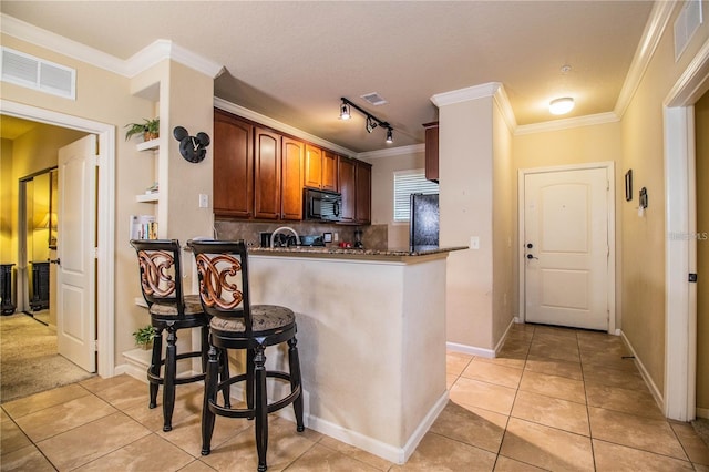 kitchen featuring kitchen peninsula, light tile patterned flooring, crown molding, and rail lighting