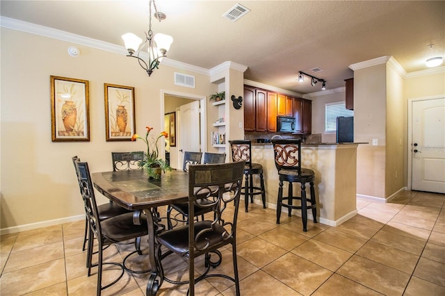 dining area with crown molding, a textured ceiling, light tile patterned floors, rail lighting, and a chandelier