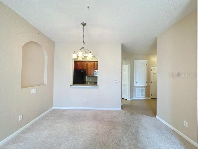 interior space with a textured ceiling, light carpet, and a chandelier