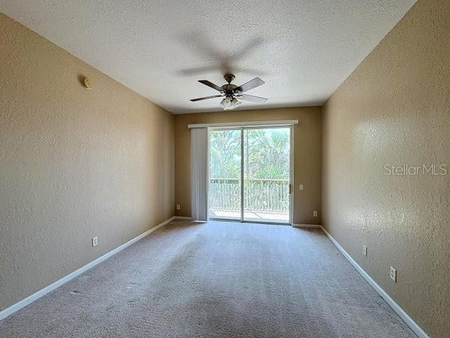 spare room with a textured ceiling, carpet flooring, and ceiling fan