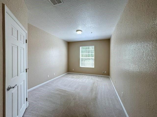 carpeted empty room featuring a textured ceiling