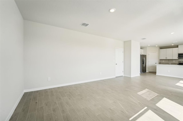 unfurnished living room featuring light hardwood / wood-style flooring and sink