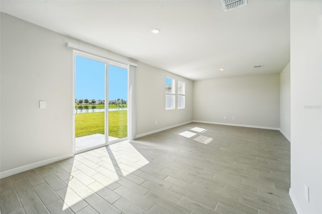 unfurnished room featuring light hardwood / wood-style flooring and a water view