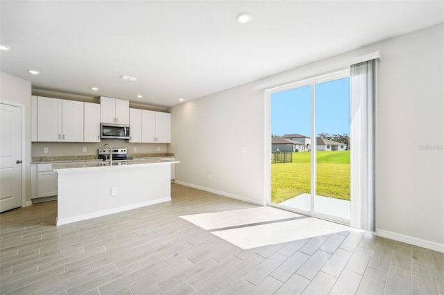 kitchen featuring white cabinets, sink, a center island with sink, appliances with stainless steel finishes, and light hardwood / wood-style floors