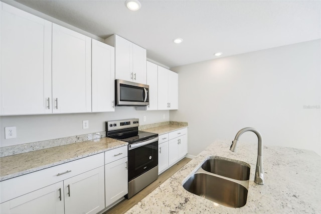 kitchen with appliances with stainless steel finishes, light stone countertops, sink, and white cabinets