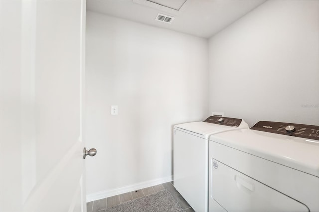 clothes washing area with wood-type flooring and washer and dryer