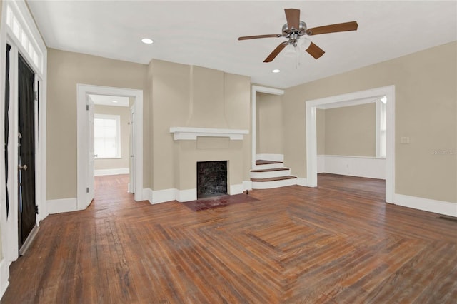 unfurnished living room with ceiling fan and dark wood-type flooring