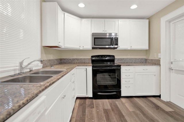 kitchen featuring sink, hardwood / wood-style flooring, dishwasher, black electric range, and white cabinetry