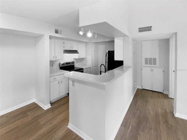 kitchen with stainless steel electric stove, white cabinets, black fridge, hardwood / wood-style flooring, and kitchen peninsula