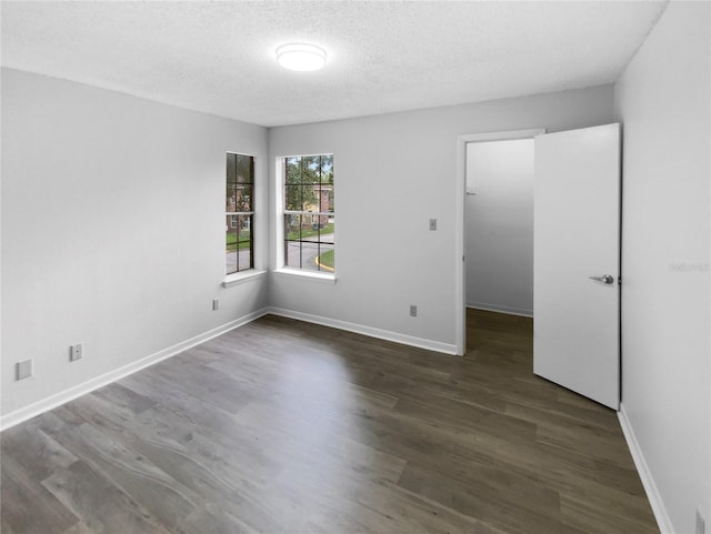 spare room with a textured ceiling and dark wood-type flooring