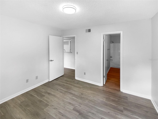 unfurnished bedroom with a textured ceiling and dark hardwood / wood-style floors