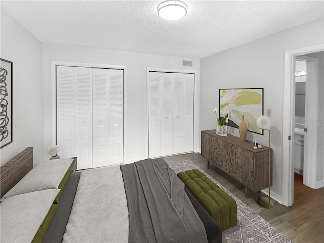 bedroom featuring a textured ceiling, two closets, and hardwood / wood-style floors