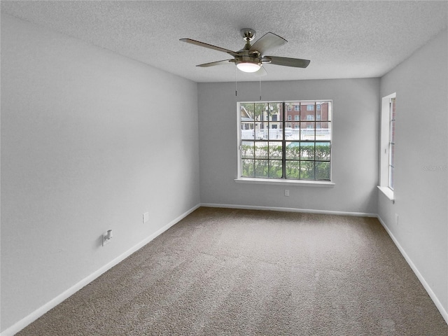 carpeted spare room featuring ceiling fan and a textured ceiling