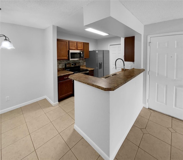 kitchen with decorative backsplash, a textured ceiling, stainless steel appliances, light tile patterned floors, and hanging light fixtures